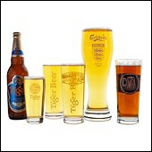 Bottle of Tiger beer with three branded Tiger glasses, a tall Carlsberb glass and CAMRA real ale group logo.
